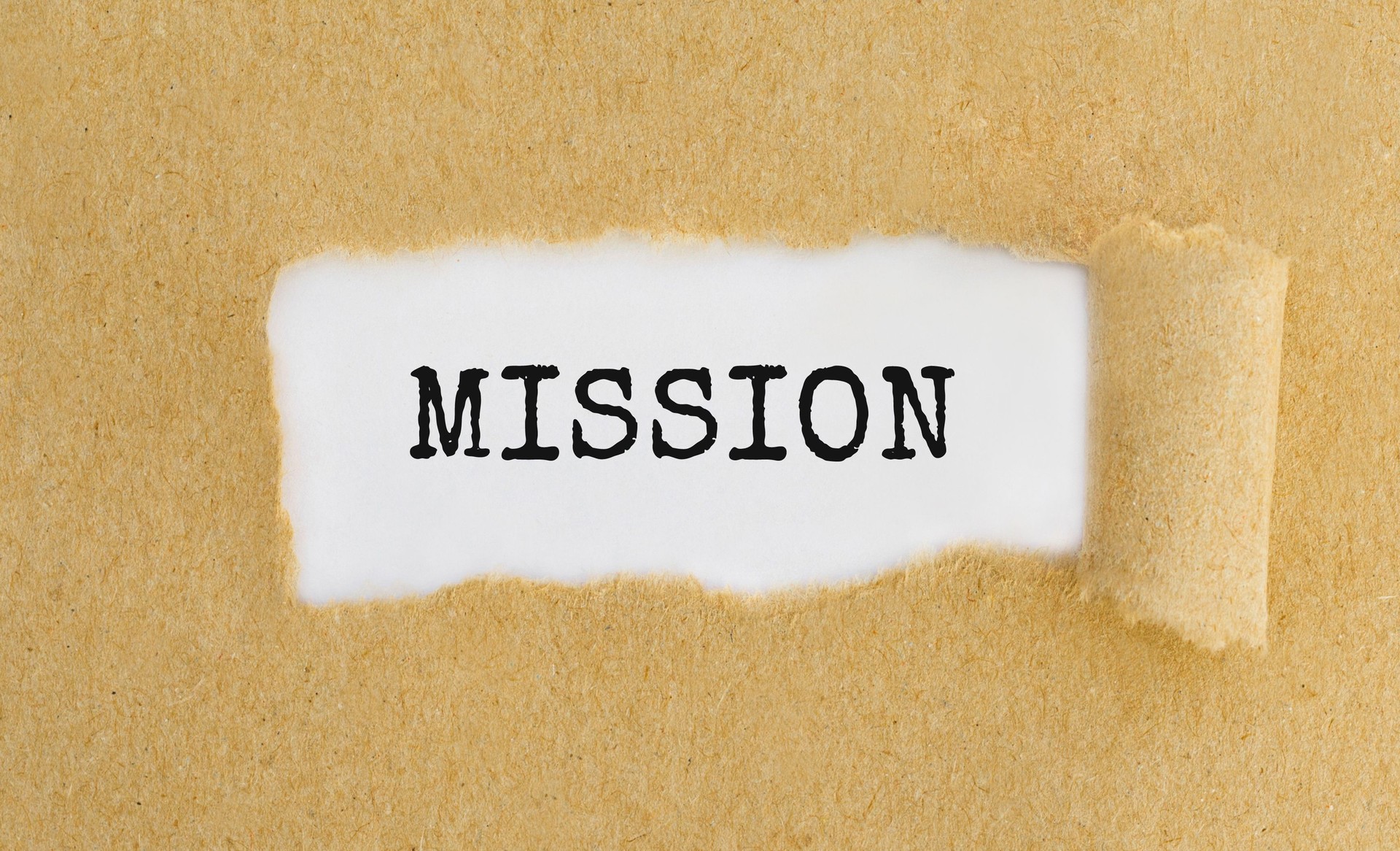 Text Mission appearing behind ripped brown paper.